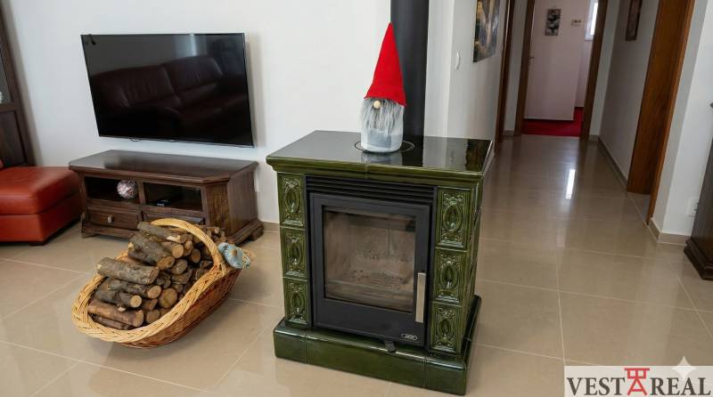 Obývačka v rodinnom dome s koženou sedačkou, drevom, krbom a elegantným lustrom..jpg