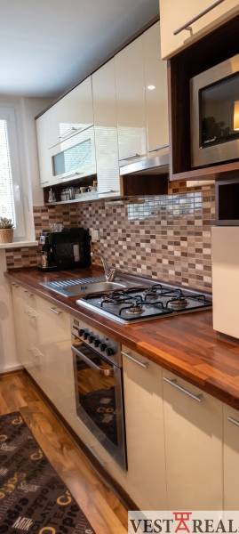 Moderná kuchyňa v 3-izbovom byte s podlahou s dreveným dekorom a mozaikovým obkladom.