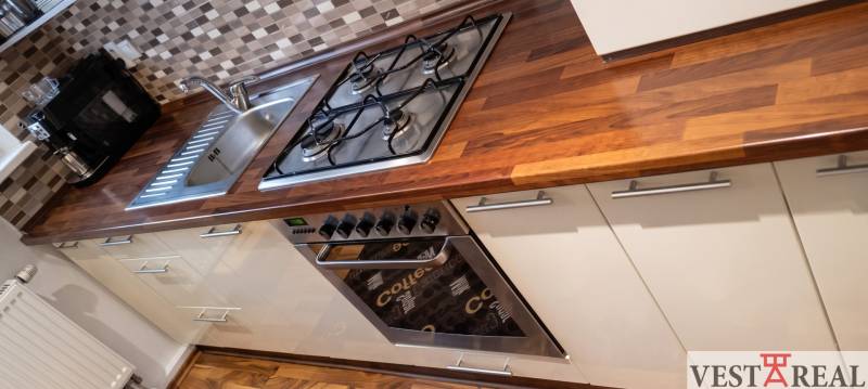 Kuchyňa v 3-izbovom byte s podlahou s dreveným dekorom a nerezovými spotrebičmi.