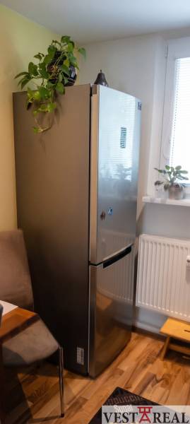 Chladnička v rohu kuchyne s rastlinami, podlaha s dreveným dekorom, 3-izbový byt.