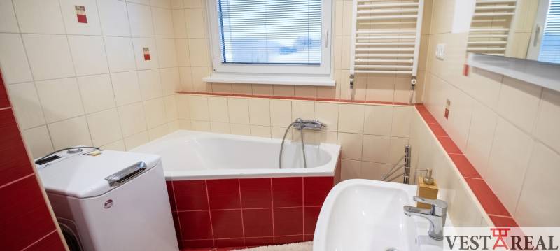 Kúpeľňa s vaňou, umývadlom a práčkou v 3-izbovom byte, svetlé obklady.