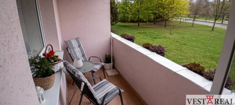 Balkón 3-izbového bytu s posedením a výhľadom na zelený park.